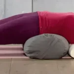Yoga Teacher in a restorative backbend on a bolster.